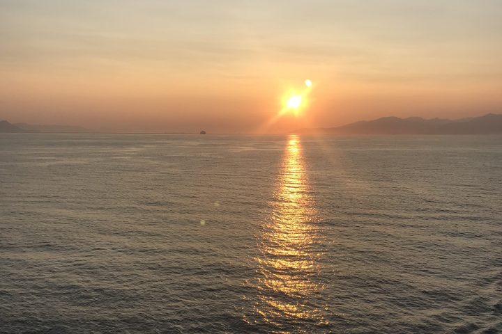 Sunset over ocean with sun reflecting on the water surface.