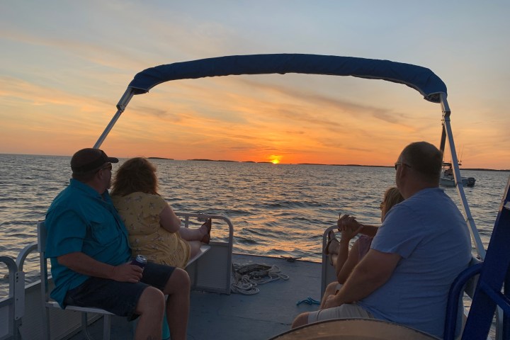People on a boat watching a sunset over the water.