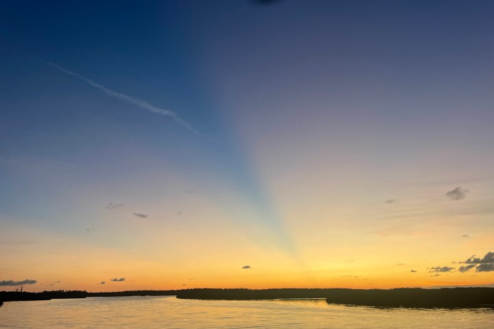 Sunset over a calm lake with scattered clouds and a colorful sky.